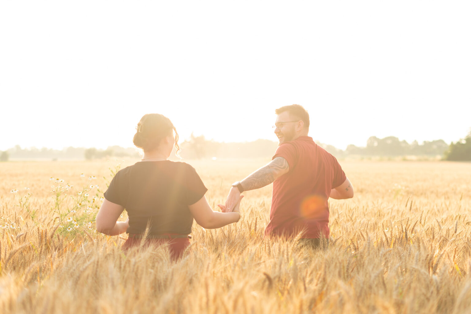 Braut und Bräutigam laufen über ein Feld und lächeln sich beim Sonnenuntergang an – Hochzeitsfotograf in Offenburg Jonathan Gäßler hält diesen Moment fest.