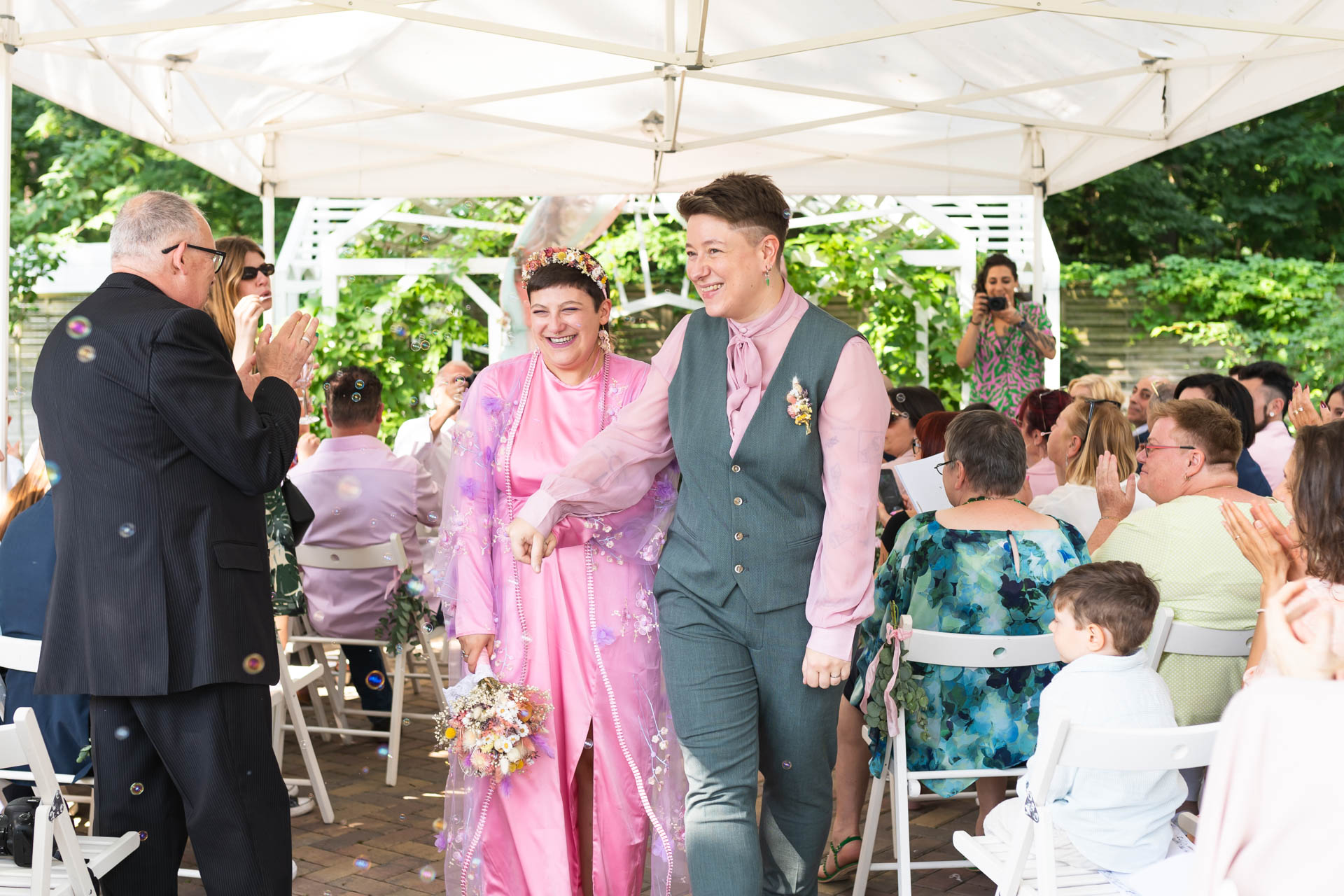 Hochzeitspaar nach Zeremonie (freie Trauung) beim Verlassen der Location. Alle applaudieren & das Paar freut sich.
