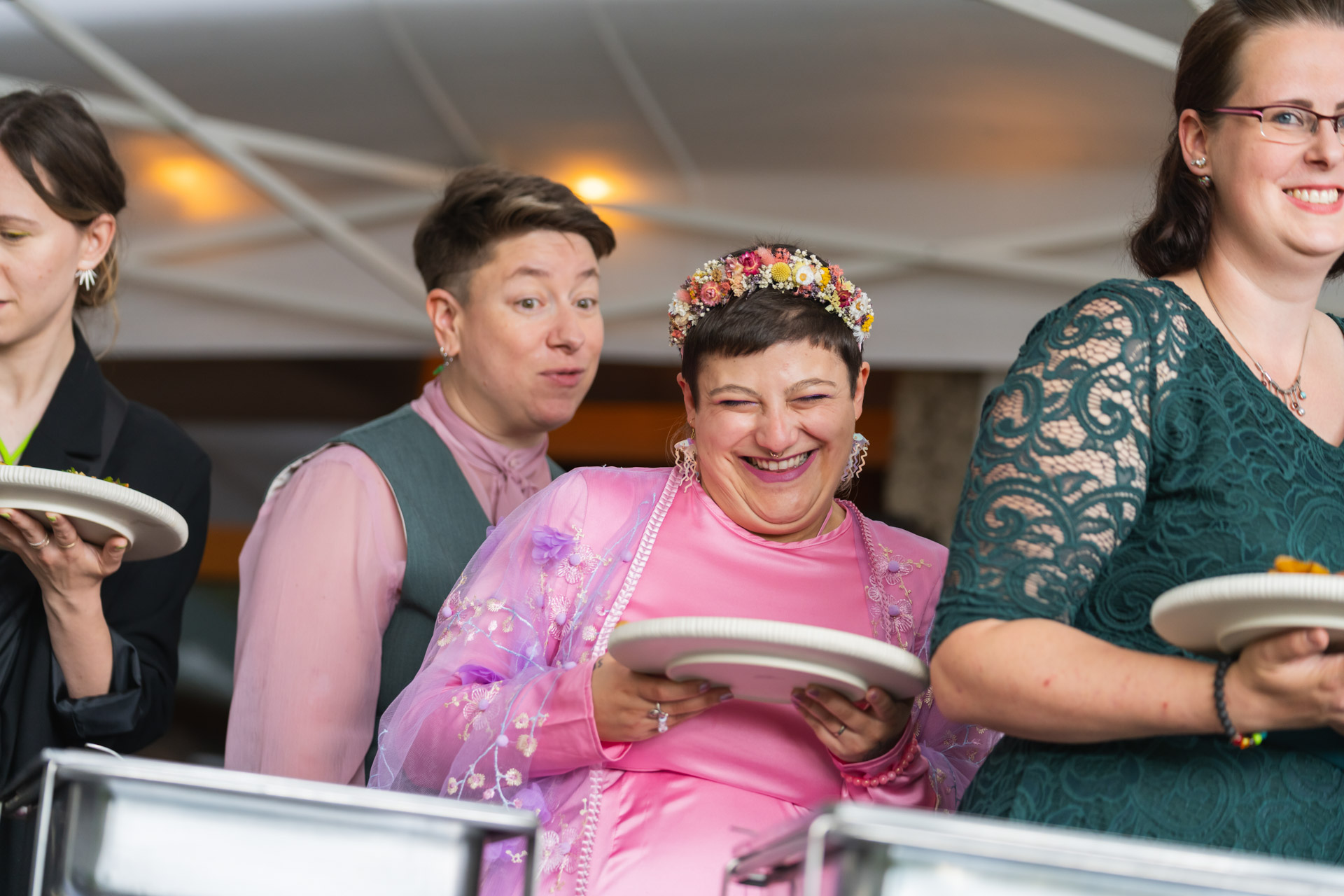 Hochzeitspaar steht an der Essensausgabe und freut sich.