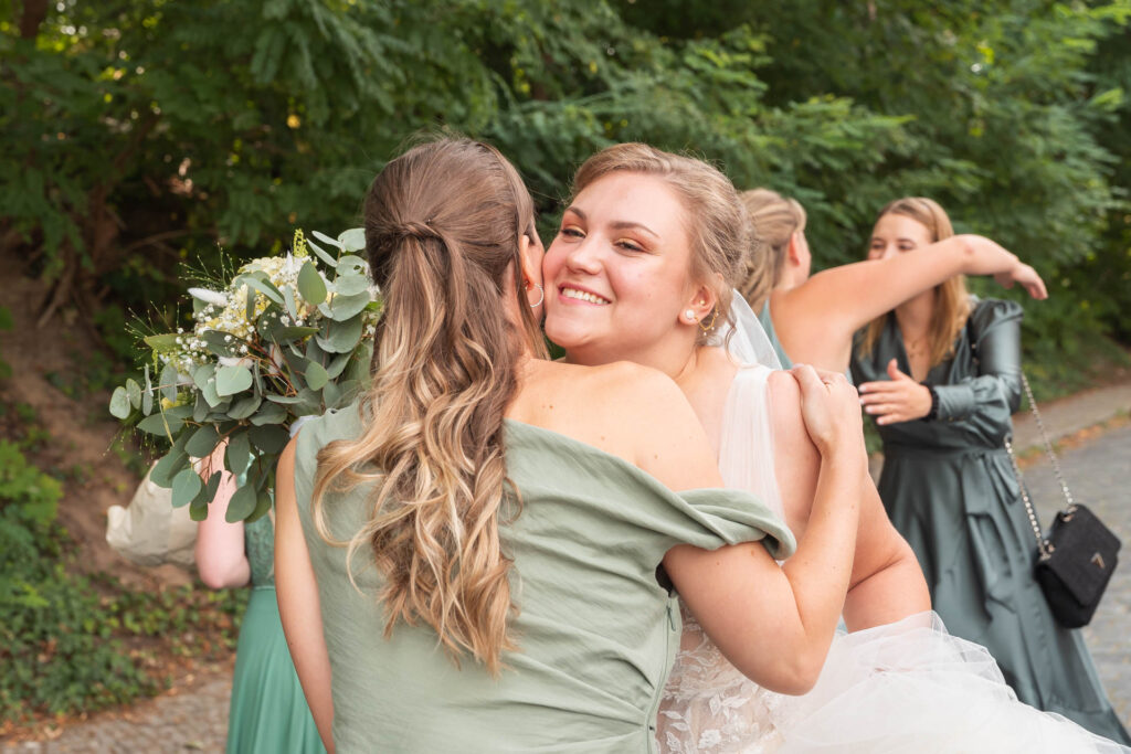 Umarmung von der Braut & einer Brautjunger vor der Trauung.
