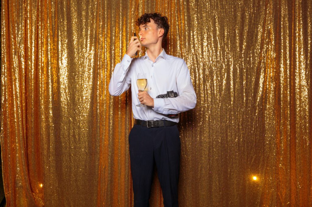 Aufnahme von Hochzeitsfotograf Jonathan Gäßler, wie er vor einer Fotowand steht und posiert.